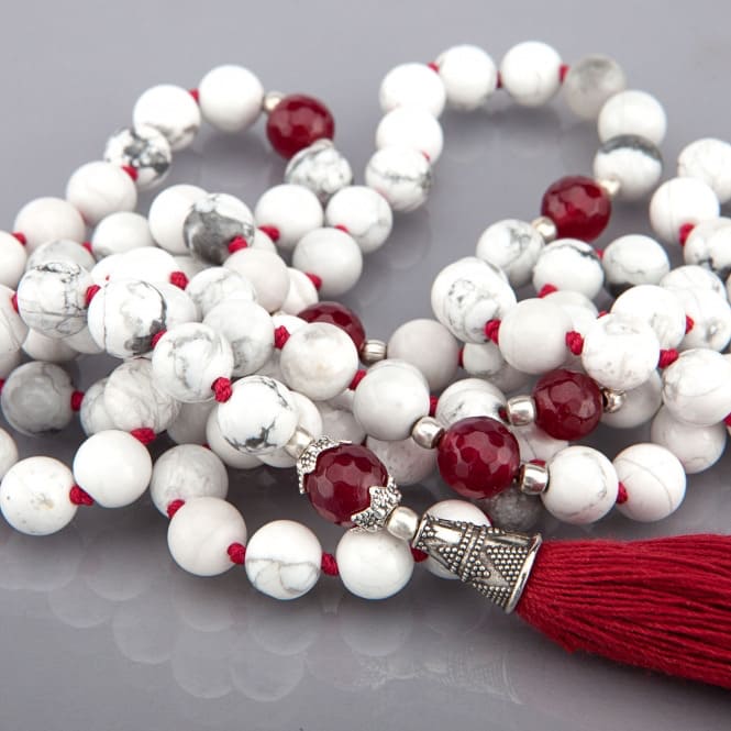 Mala in 108 perline Howlite bianca intercalata ogni 11 grani da perline di onice rosso, annodati singolarmente, e nappina rossa, particolare guru bead