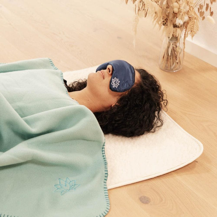 coperta Asana con ricamo loto, color verdeacqua, distesa su modella sdraiata