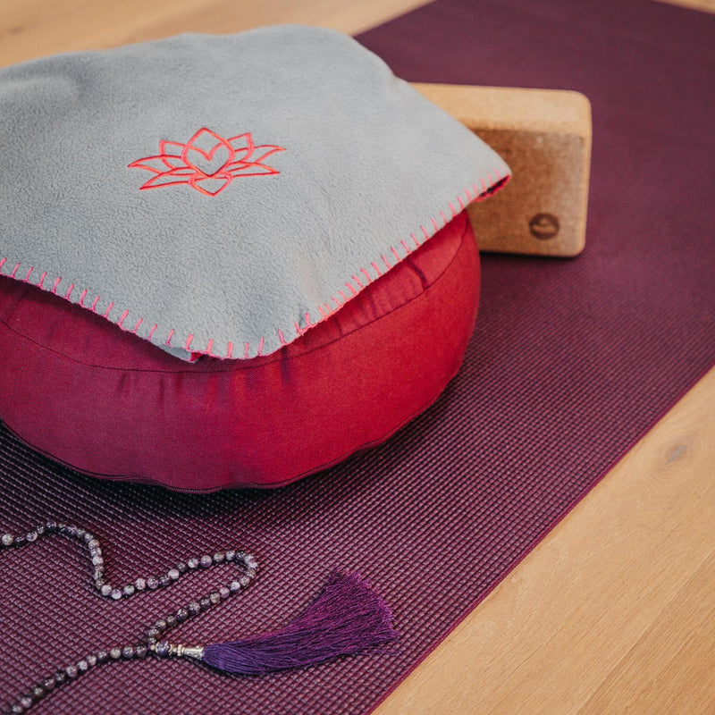 coperta Asana con ricamo loto, color grigia appoggiata su cuscino meditazione su tappetino yoga