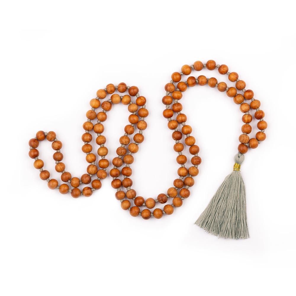 Mala in grani di legno di sandalo profumato, annodati singolarmente ad ogni grano, con nappine di colore grigio perla, disteso.