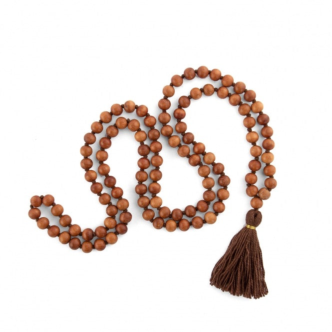 Mala in grani di legno di sandalo profumato, annodati singolarmente ad ogni grano, con nappine di colore marrone, disteso.